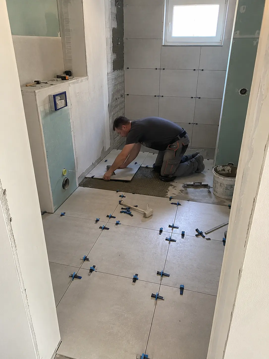 Fliesenleger beim Verlegen von Bodenfliesen im Badezimmer in Hamburg