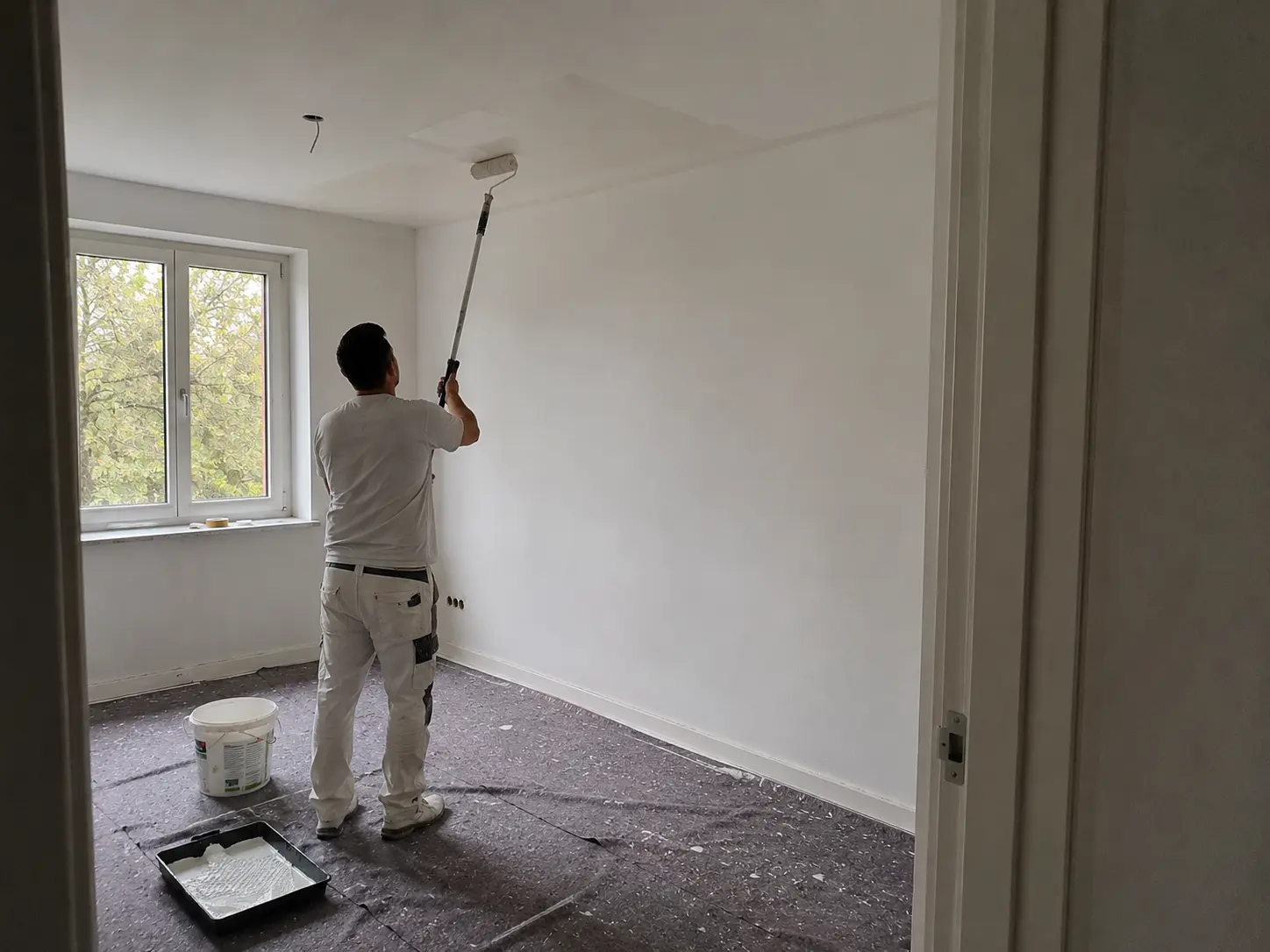 Maler beim Deckenanstrich mit sauberer Abklebung in einem Wohnraum in Hamburg
